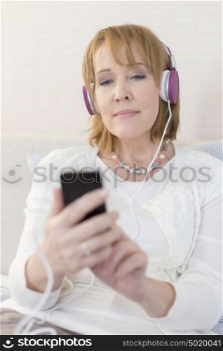 Mature woman using smartphone while sitting at home