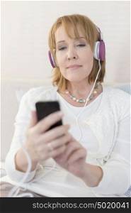 Mature woman using smartphone while sitting at home
