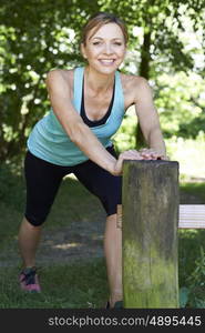 Mature Woman Warming Up Before Exercising In Countryside