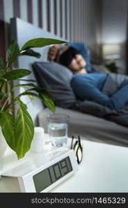 Mature woman wearing black sleeping mask, lying in bed in bedroom. Mature Woman Wearing Black Sleep Mask, Lying in Bed