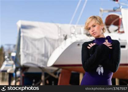 Mature woman wearing purple dress and posing, sailboat on background