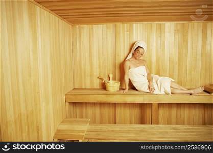 Mature woman wearing towel sitting in a sauna