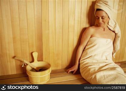 Mature woman wearing towel sitting in a sauna