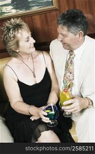 Mature woman with a senior man holding glasses of cocktail and looking at each other