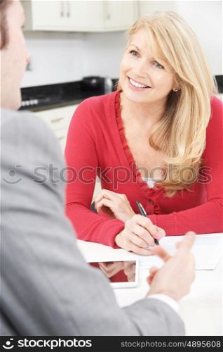 Mature Woman With Financial Advisor Signing Document At Home