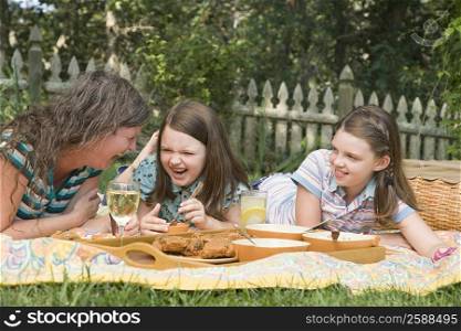 Mature woman with her two daughters having picnic in a park