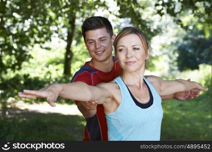 Mature Woman With Yoga Coach In Park