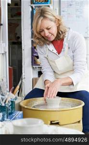 Mature Woman Working At Potters Wheel In Studio