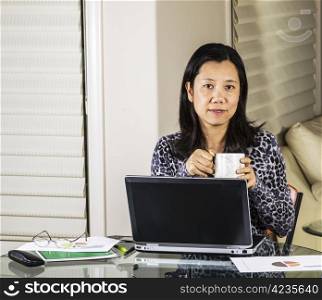 Mature women drinking coffee while working from home office