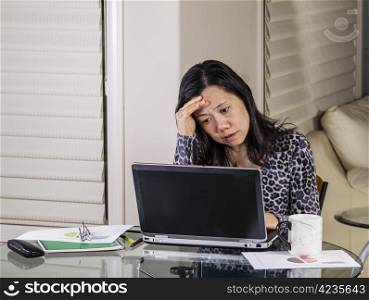 Mature women looking worried while working in home office