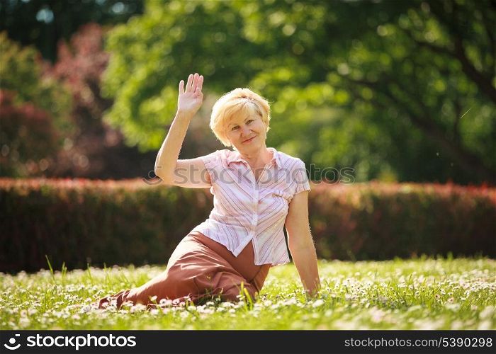 Maturity. European White Hair Woman sitting on Grass and having Fun