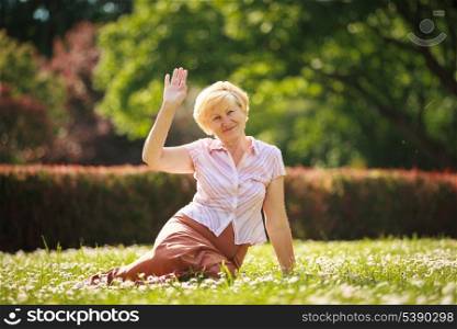 Maturity. European White Hair Woman sitting on Grass and having Fun