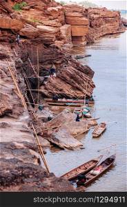 MAY 17, 2010 , Ubon Ratchathani, Thailand - Large Sand stone canyon cliff shoreline of Mekong river and local Thai fishermans at Ban Pha Chan.
