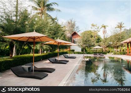 MAY 21, 2014 Krabi, THAILAND - Resort pool in tropical coconut garden, umbrellas and pool beds, Koh Lanta tropical resort outdoor space in summer