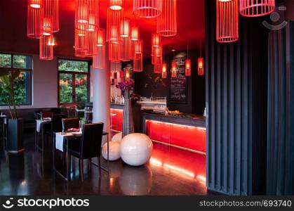 MAY 22,2014 Koh Lanta, Krabi, Thailand - Modern vibrant interior bar lounge with black and white tone furnitures, sexy red pedant lamps, red ceiling and black shiny floor.