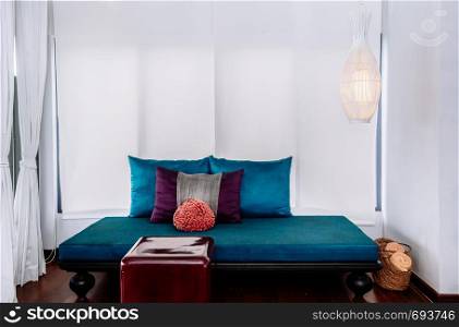 MAY 22,2014 Koh Lanta, Krabi, Thailand - White modern minimal living room interior with colorful furnitures, blue sofa couch with asian style pillows and red acrylic table. Modern simple and clean interior design