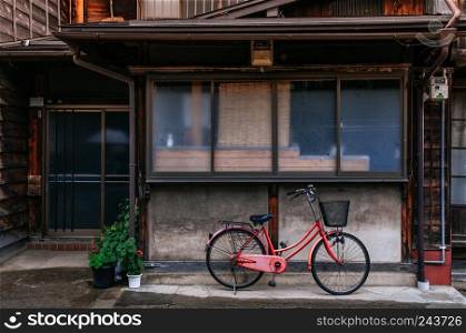 MAY 29, 2013 Nagano, Japan - Old vinatge red bicycle in front of old house in Narai Post town (Narai-Juku). The midpoint town on Nakasendo road, Edo period trading route between old Tokyo and Kyoto