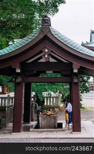 MAY 30, 2013 Nagoya, JAPAN - Asian Japanese family mother and son washing their hands at Temizuya wooden holy water pavilion at Nittai-ji temple