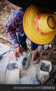 MAY 8, 2010 Bangkok, Thailand - Asian male construction labour use cutting wheel to cut granite stone tile at building construction site with no safety equipment