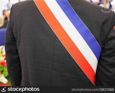 Mayor of French town with French tricolour flag mayoral sash. French mayor with sash
