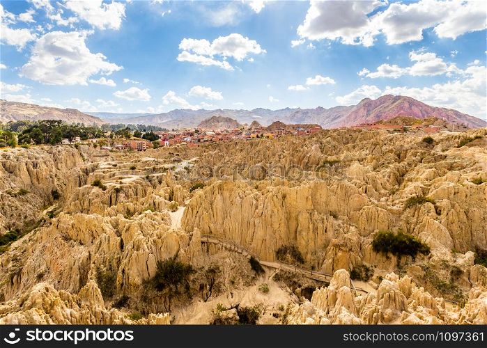 Maze of Moon Valley or Valle De La Luna eroded sandstone spikes, with La Paz city suburb and mountains in the background, Bolivia