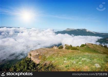 Meadow in the mountains over the clouds