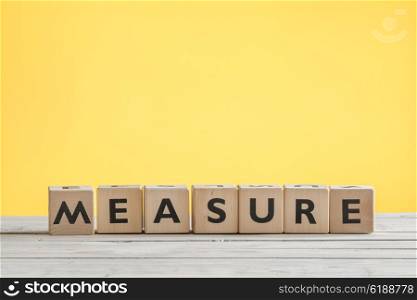 Measure sign with wooden cubes on a yellow background