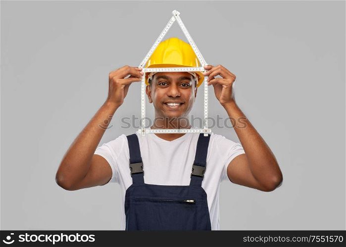 measurement, construction and building - happy smiling indian worker or builder in helmet with folding ruler in shape of home over grey background. happy indian builder with ruler in shape of home