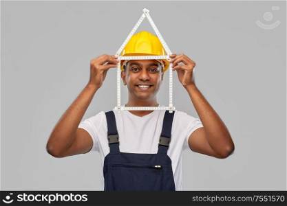 measurement, construction and building - happy smiling indian worker or builder in helmet with folding ruler in shape of home over grey background. happy indian builder with ruler in shape of home