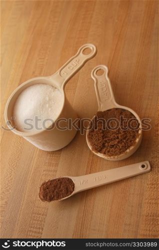 Measuring cups with cocoa, brown and white sugar.