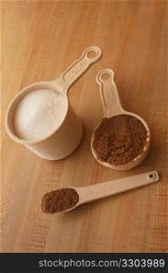Measuring cups with cocoa, brown and white sugar.