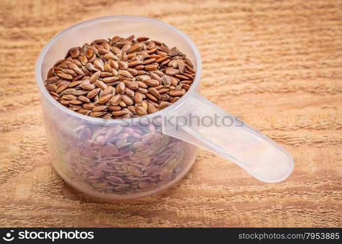 measuring scoop of brown flax seeds against textured cedar wood