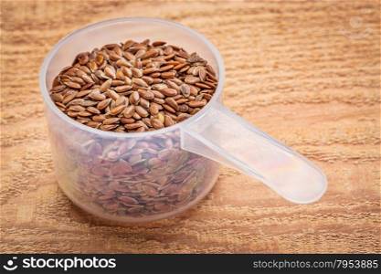 measuring scoop of brown flax seeds against textured cedar wood