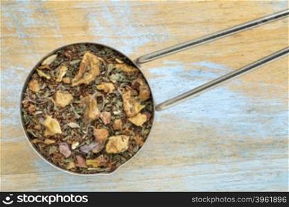 Measuring scoop of chocolate rooibos mint tea against blue painted wood