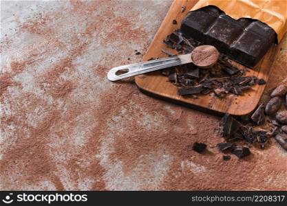 measuring spoon with cocoa powder crushed chocolate bar chopping board