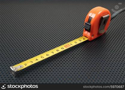Measuring tape on a metallic background with perforation of round holes
