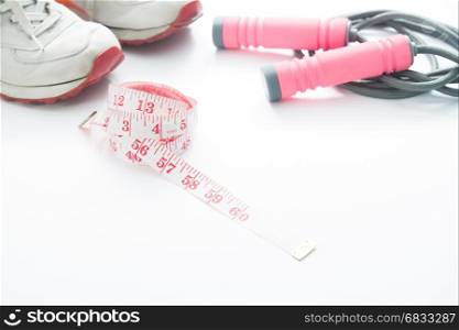 Measuring tape, sport shoes and jump rope in pink color on white background, Working out and diet concept