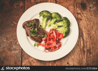 Meat and vegetables including broccoli and red peppers on a plate