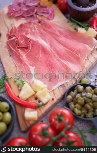 Meat antipasto platter on stone table - Sliced fuet salami sausage, prosciutto or jamon ham.. Meat antipasto platter on stone table - Sliced fuet salami sausage, prosciutto or jamon ham