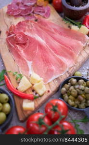 Meat antipasto platter on stone table - Sliced fuet salami sausage, prosciutto or jamon ham.. Meat antipasto platter on stone table - Sliced fuet salami sausage, prosciutto or jamon ham