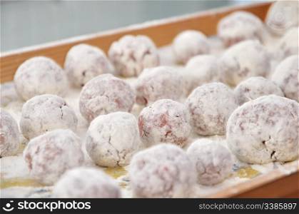 Meat ball in the flour on a tray ready to be cooked. Meatball sprinkled with flour