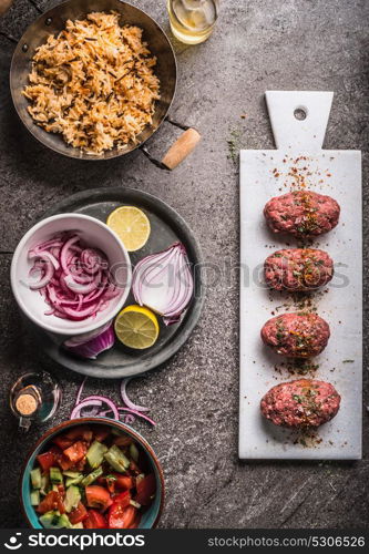 Meat balls cooking preparation with rice dish and salad on rustic kitchen table background, top view