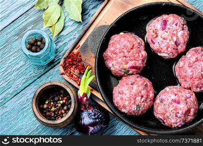 Meat balls from raw beef force-meat in iron cast pan. Raw uncooked meatballs