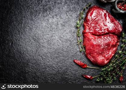 meat beef steak with herbs and spices on dark background, top view, place for text