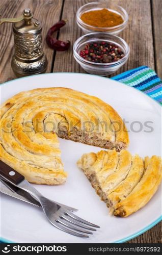 Meat burekas from puff pastry on wooden background. Studio Photo
. Meat burekas from puff pastry on wooden background