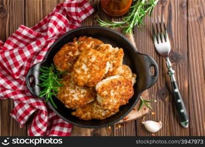 meat cutlets in frying pan on wooden rustic table
