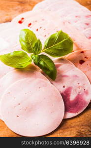 Meat delicatessen plate decorated with basil leaves on a black background. Variety of processed cold meat products