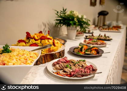 Meat dish and other snacks on the festive table in the restaurant. Various meat snacks and other appetizers on holiday table. Catering wedding table.