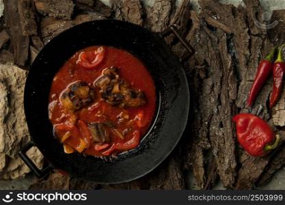 meat dish in a frying pan against the background of the bark of a tree. dish on a tree bark