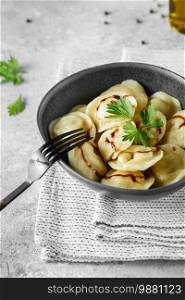 Meat dumplings - russian pelmeni, ravioli with meat in a grey bowl.  Food photography